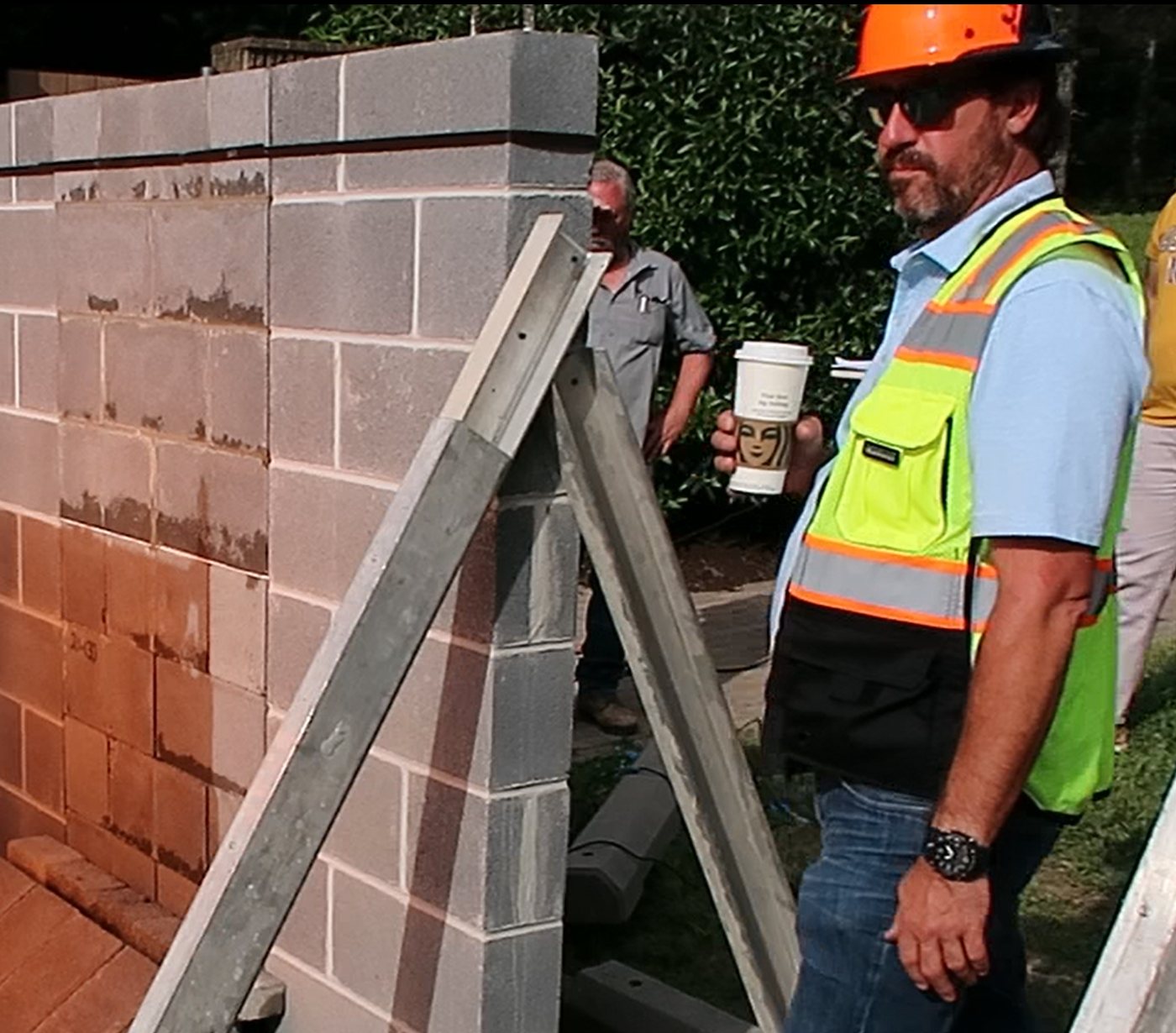 Shawn Benn in hard hat and hi-vis on site at the independent NCMA water-dehydration test, beside the test wall